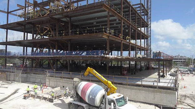 Construction progress of the Fort Lauderdale U.S. Courthouse with a crane lifting materials and multiple floors/levels under construction.